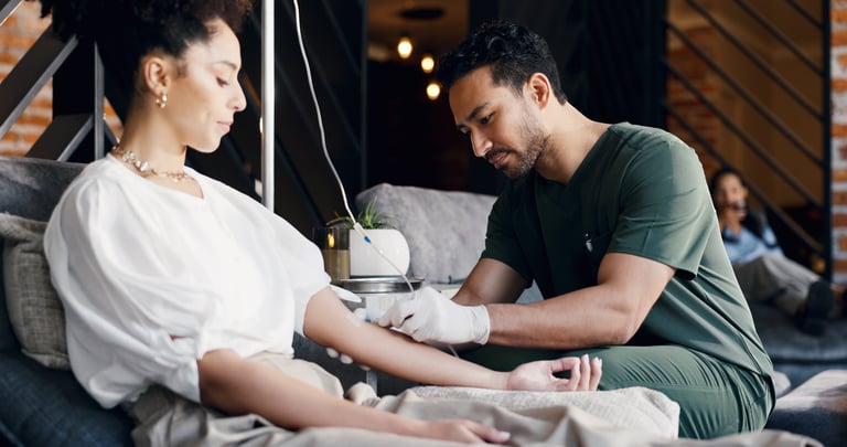 Patient, nurse or IV therapy in lounge with drip preparation, mineral infusion or immune health. People, healthcare worker and injection with intravenous fluid for saline solution at wellness center
