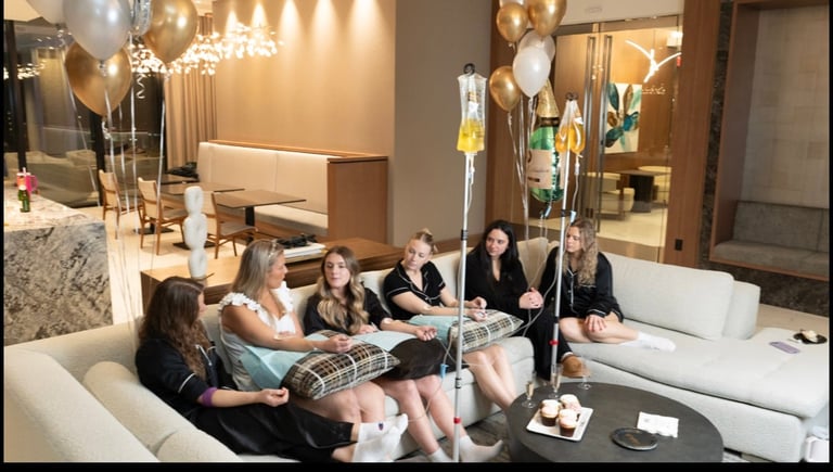 Group of women sitting on white couches in a modern living room with champagne balloons and elegant decor